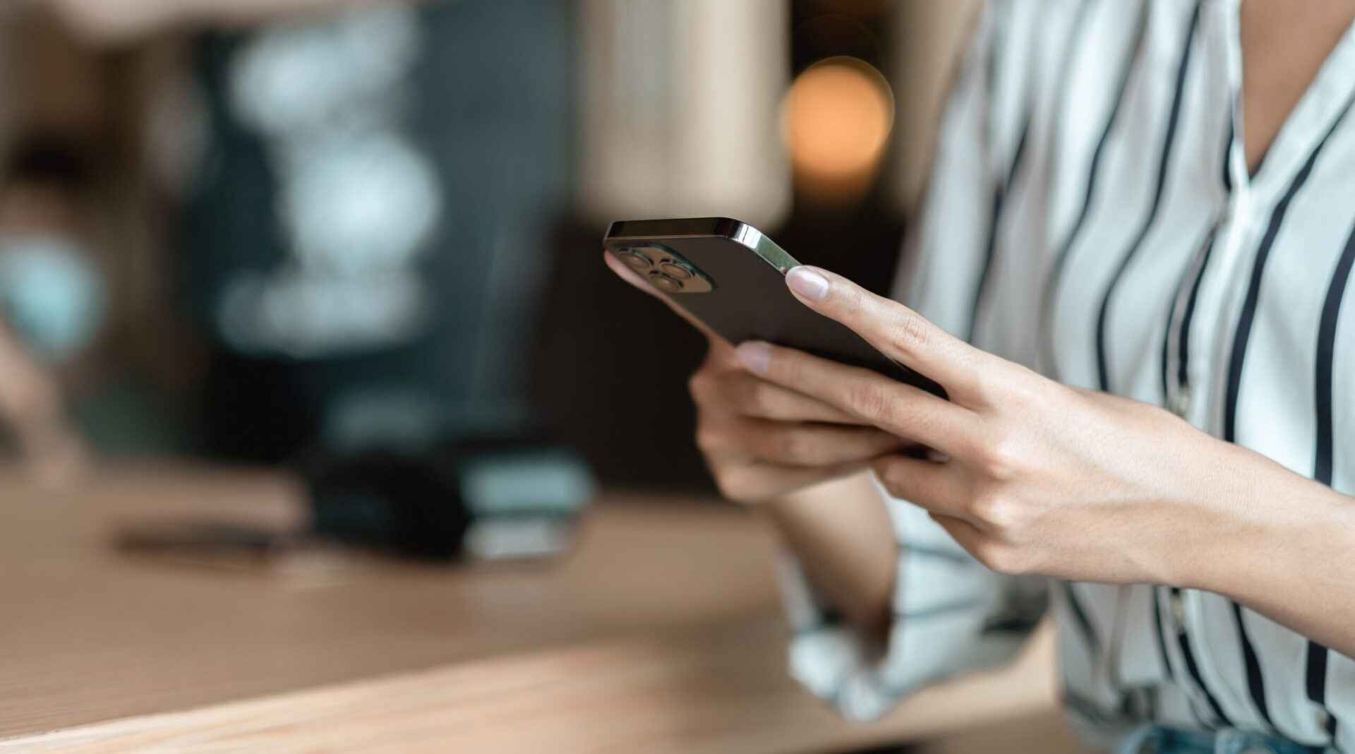 カフェでスマートフォンを操作する女性の手元